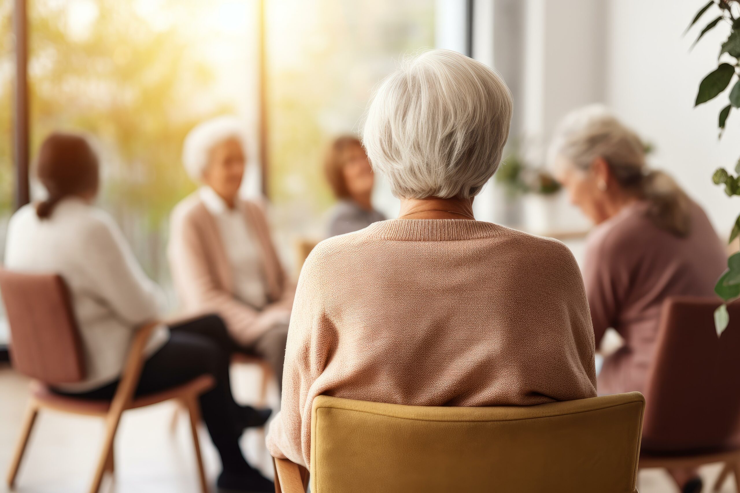 Elderly woman sitting with her back turned during group therapy session